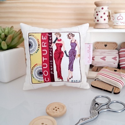 Almofada branca com estampa de moda e acessórios de costura sobre uma mesa branca