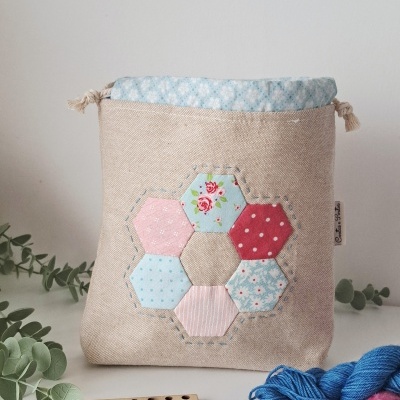 Bolsa bege com padrão hexagonal colorido e materiais de artesanato ao redor