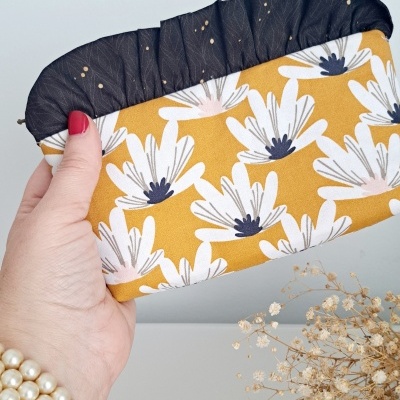 Mala pequena de mão amarelo com flores brancas e parte superior preta com pontos dourados