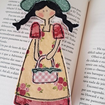 Marcador de livros de boneca em tecido colorido sobre livro aberto