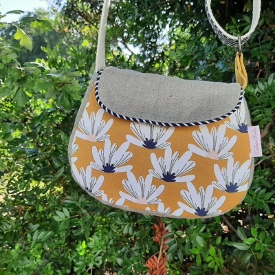 Bolsa pequena de ombro com padrão floral amarelo e cinzento pendurada em árvore
