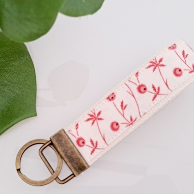 Chaveiro tecido branco com padrão floral vermelho e acabamento metálico
