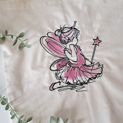 Saco de tecido cru com ilustração de fada menina bordada em preto e rosa.