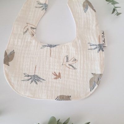 Babete bege com padrão de pássaros e plantas