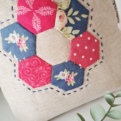 Bolsa bege com aplicação de hexágonos florais azul e rosa e costura azul