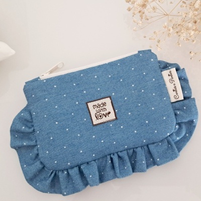 Bolsa azul com bolinhas brancas, folhos e etiquetas na superfície branca