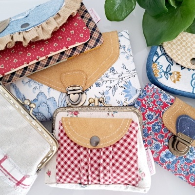 Diversas carteiras coloridas em tecidos variados com fechos metálicos