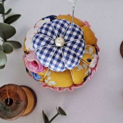 Alfineteiro flor azul e amarelo com bobinas de linha e folhas verdes