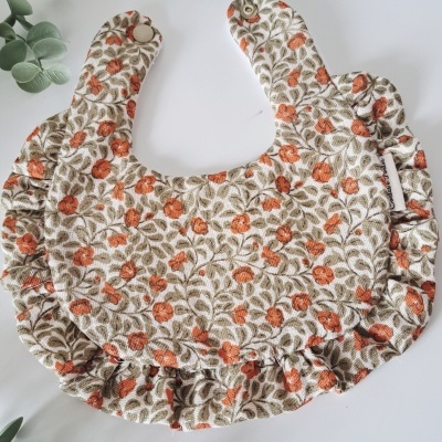 Babete de tecido floral cor creme com botões de pressão e folhos