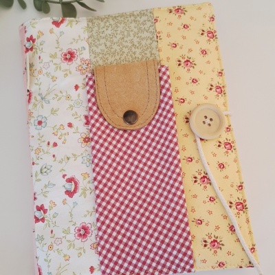 Capa de tecido patchwork com padrões florais e xadrez, fecho de botão metálico e botão de madeira