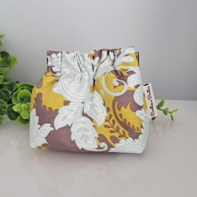 Bolsa pequena de tecido com padrão floral branco, castanho e amarelo com etiqueta Cristina Brasil