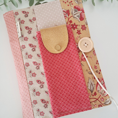Capa em tecido patchwork com botão e bolso, em tons rosa, bege e vermelho