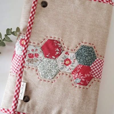 Capa de tecido beige com detalhe patchwork e bordas xadrez vermelhas e brancas