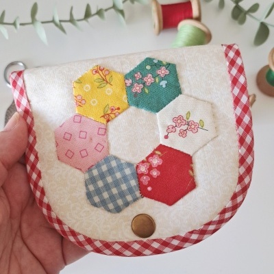Carteira patchwork com hexágonos coloridos e bordas xadrez vermelhas