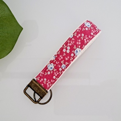 Pulseira chaveiro com padrão floral rosa e fivela metálica