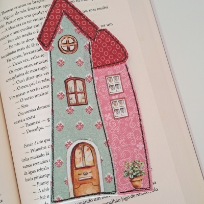 Marcador de livros tecido casa colorido em livro aberto.
