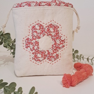 Bolsa de tecido com padrão floral vermelho e detalhes de crochê cor de rosa