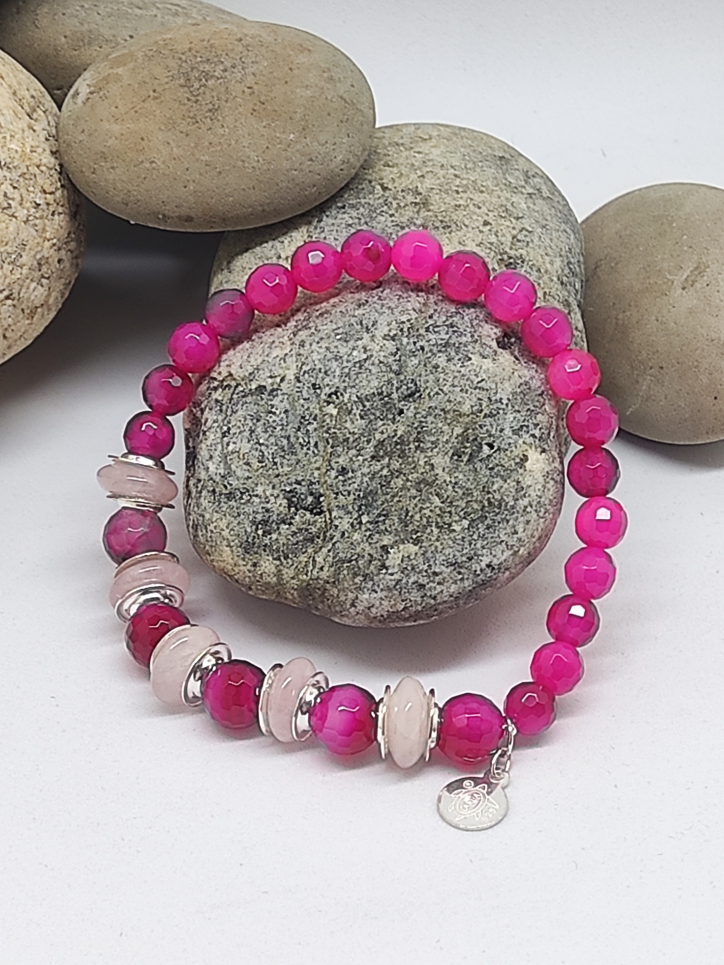 Pulseira de contas rosas facetadas com discos rosa claro e detalhes prateados sobre pedras naturais