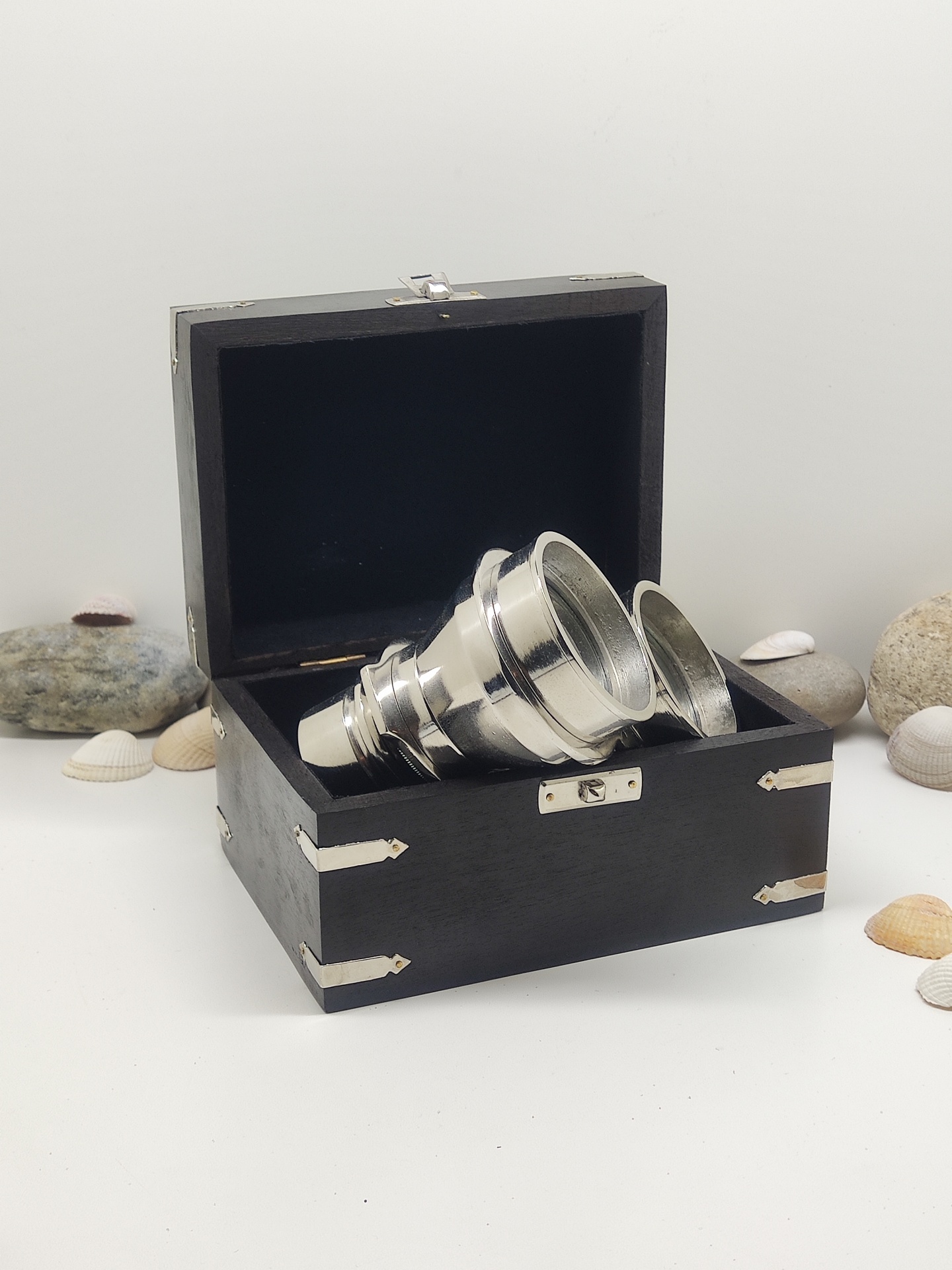 Caixa preta com copos de metal empilhados e conchas ao redor