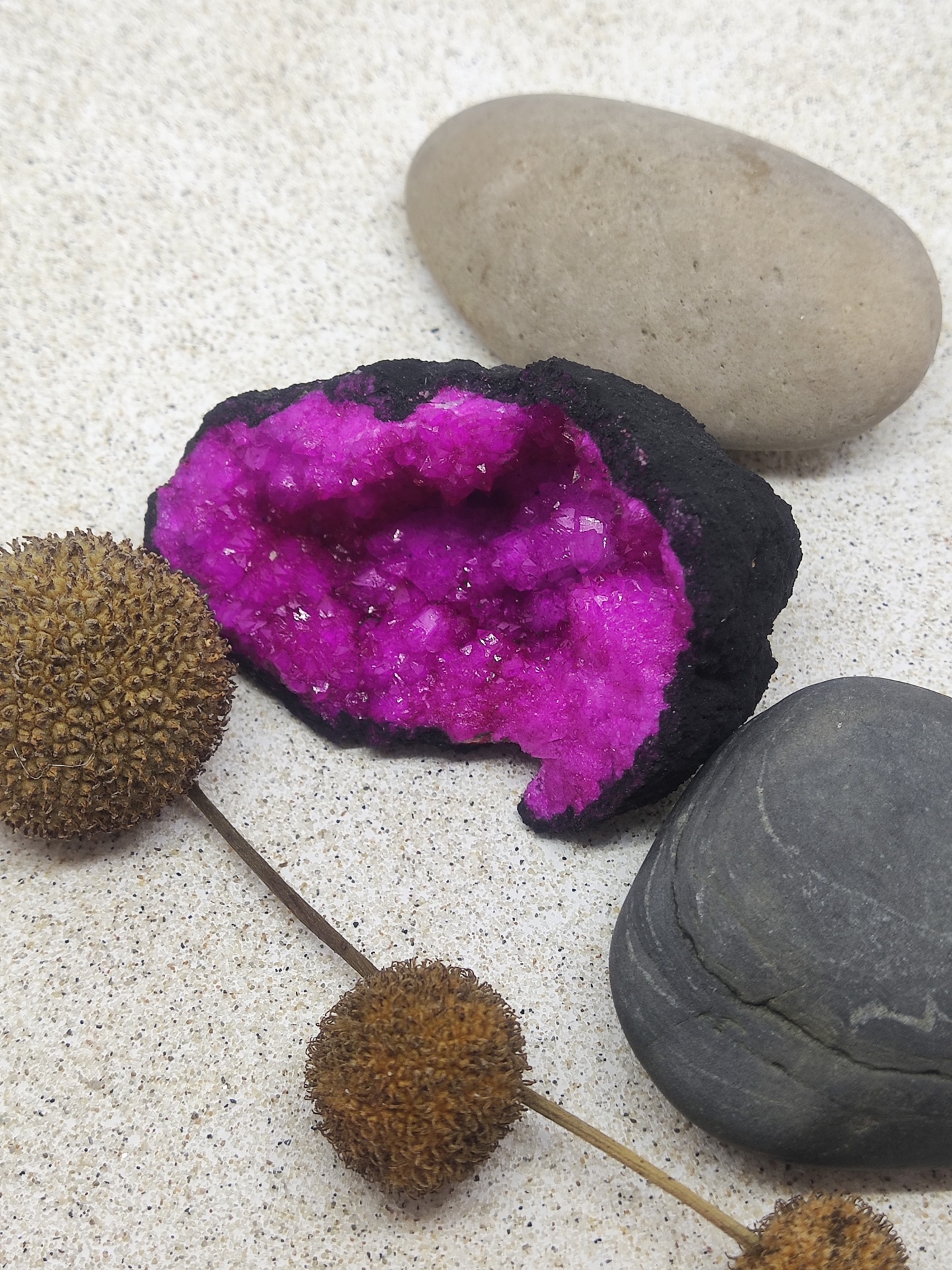 Geodo com cristais roxos, pedras naturais e objetos marrons sobre fundo branco