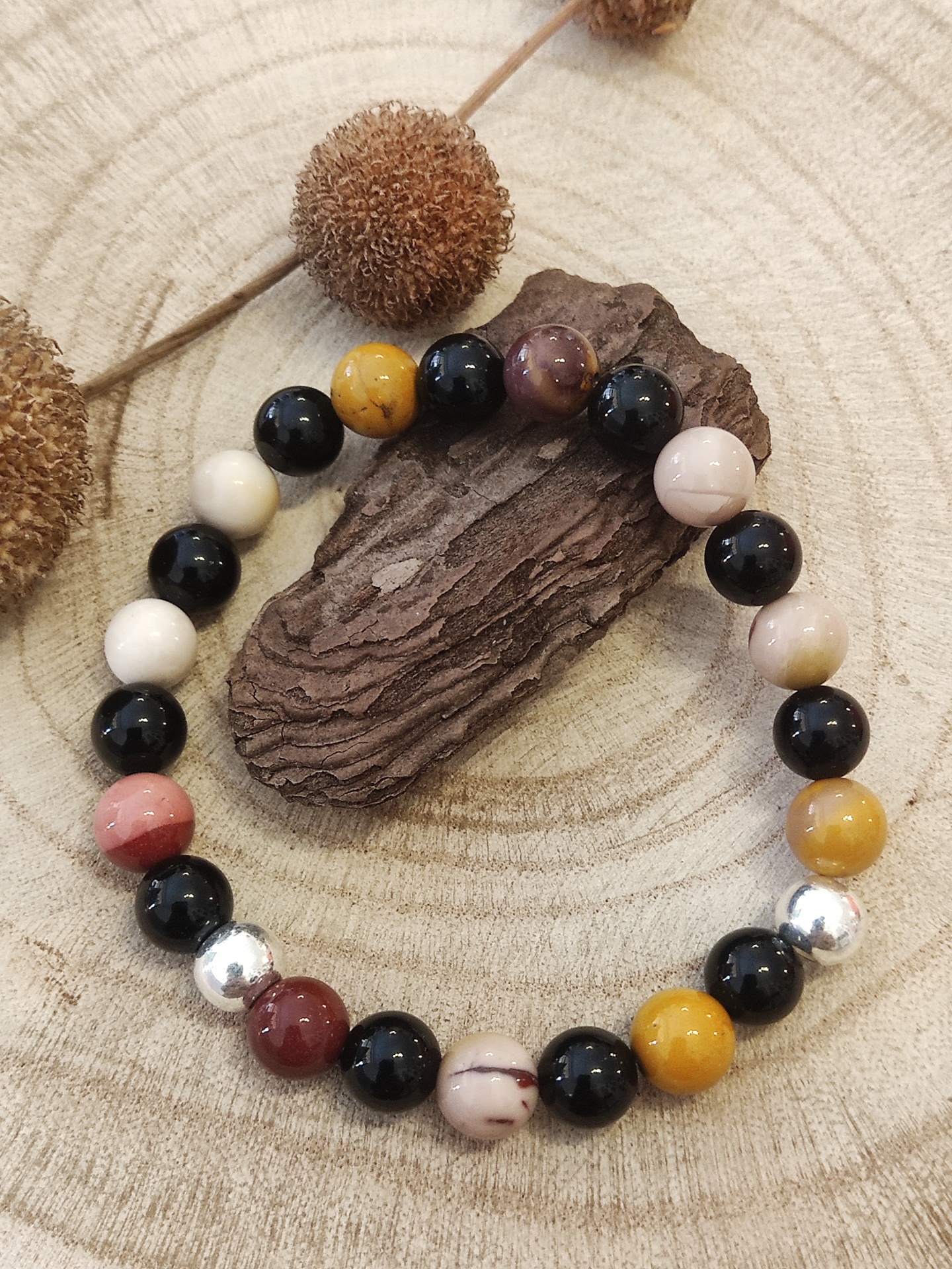 Pulseira colorida de contas sobre madeira clara e escura com decoração natural