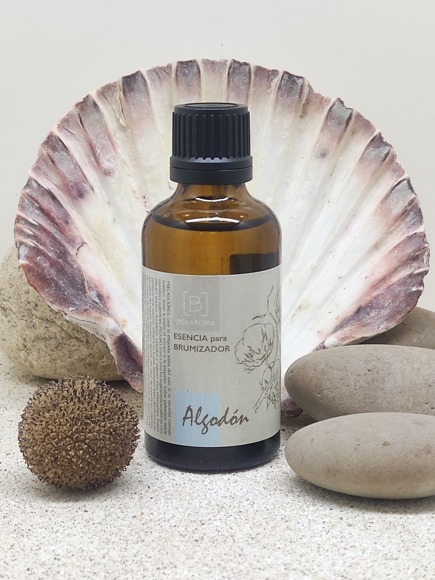 Frasco âmbar de essência para brumizador com concha e pedras ao redor