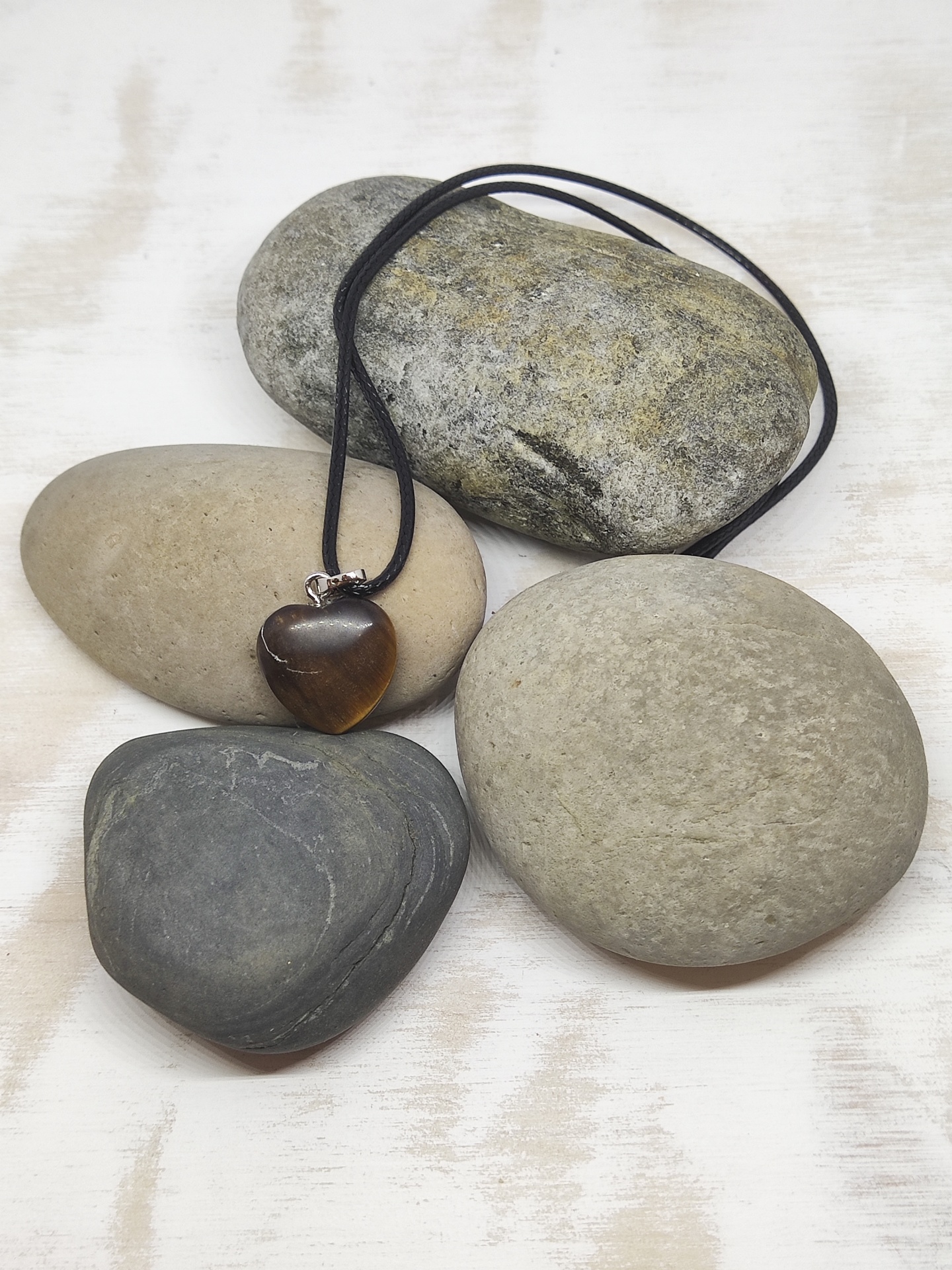 Colar com pendente castanho coração sobre pedras cinzentas