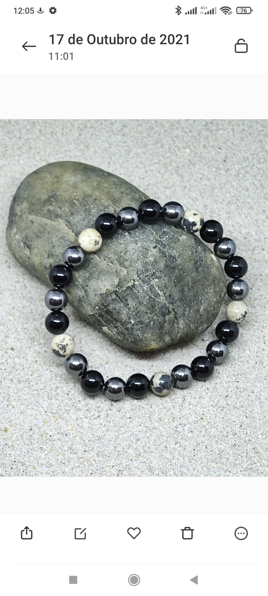 Pulseira de contas pretas, cinzentas e bege sobre pedra cinza