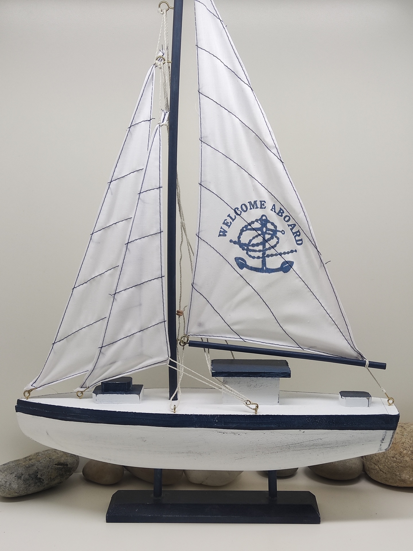 Barco decorativo de madeira branco e azul com velas brancas e texto 'WELCOME ABOARD'