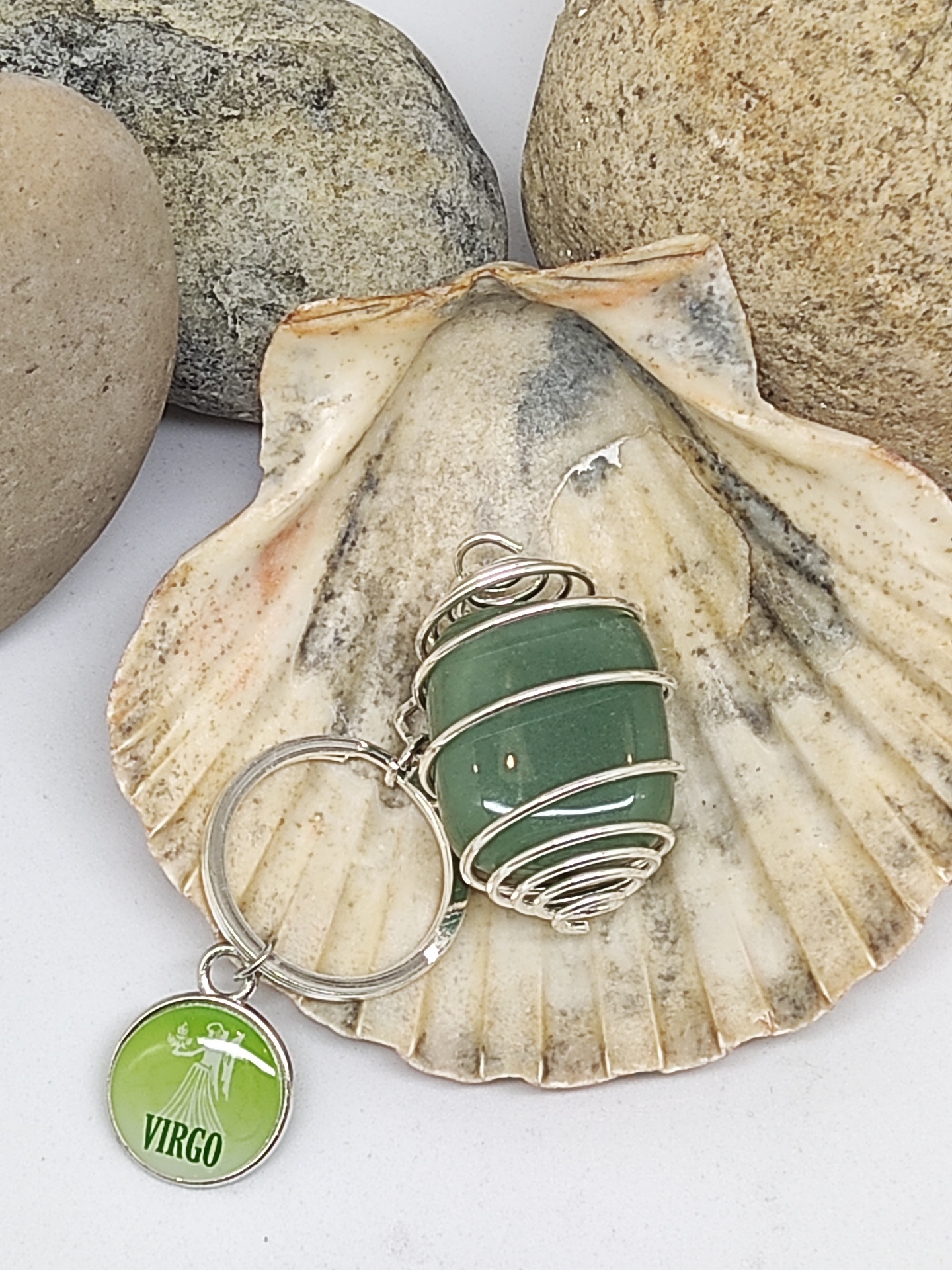 Chaveiro com pedra verde e medalha VIRGO sobre concha natural