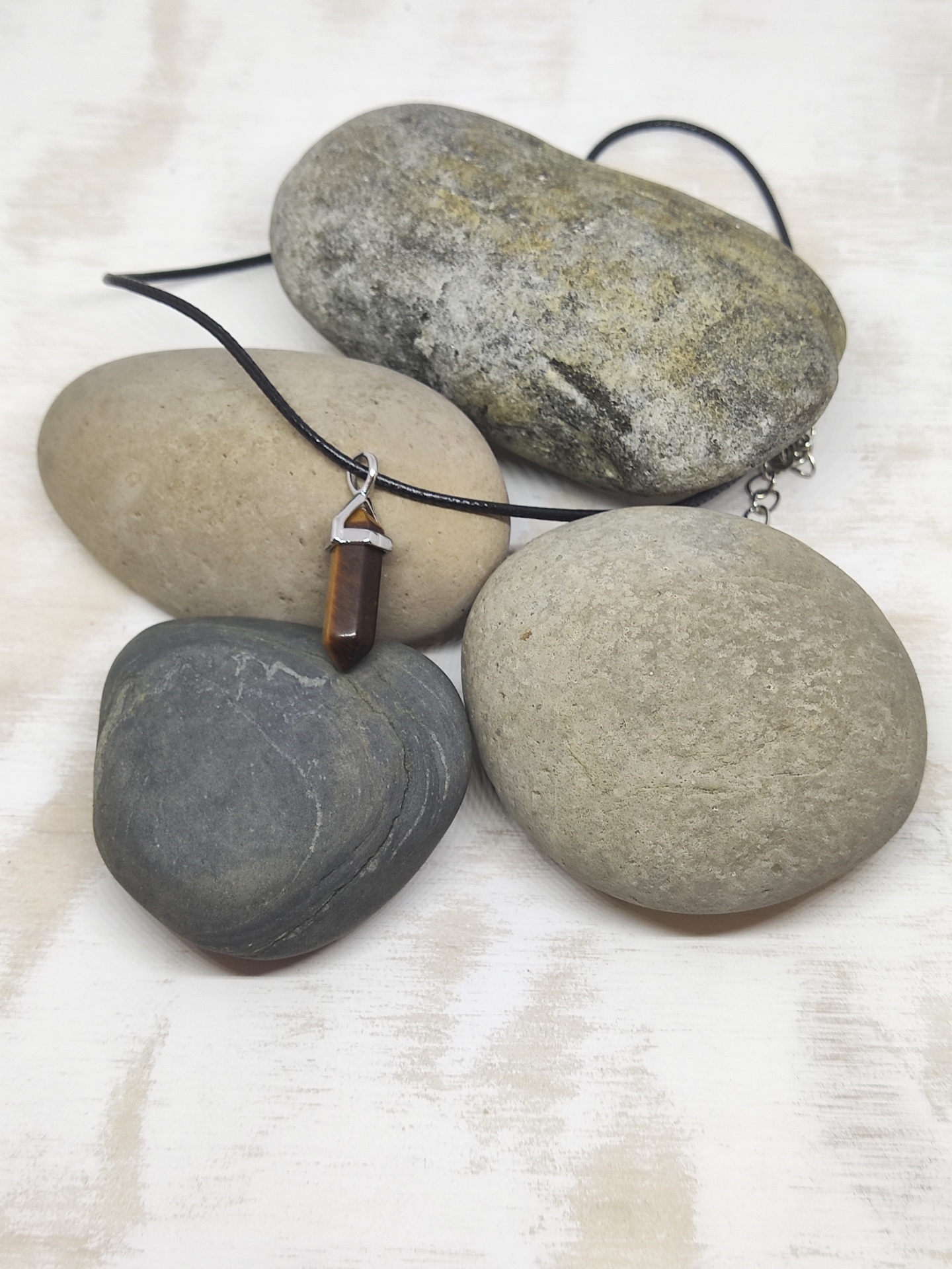 Colar com pendente castanho em pedra e metal sobre pedras naturais de vários tons