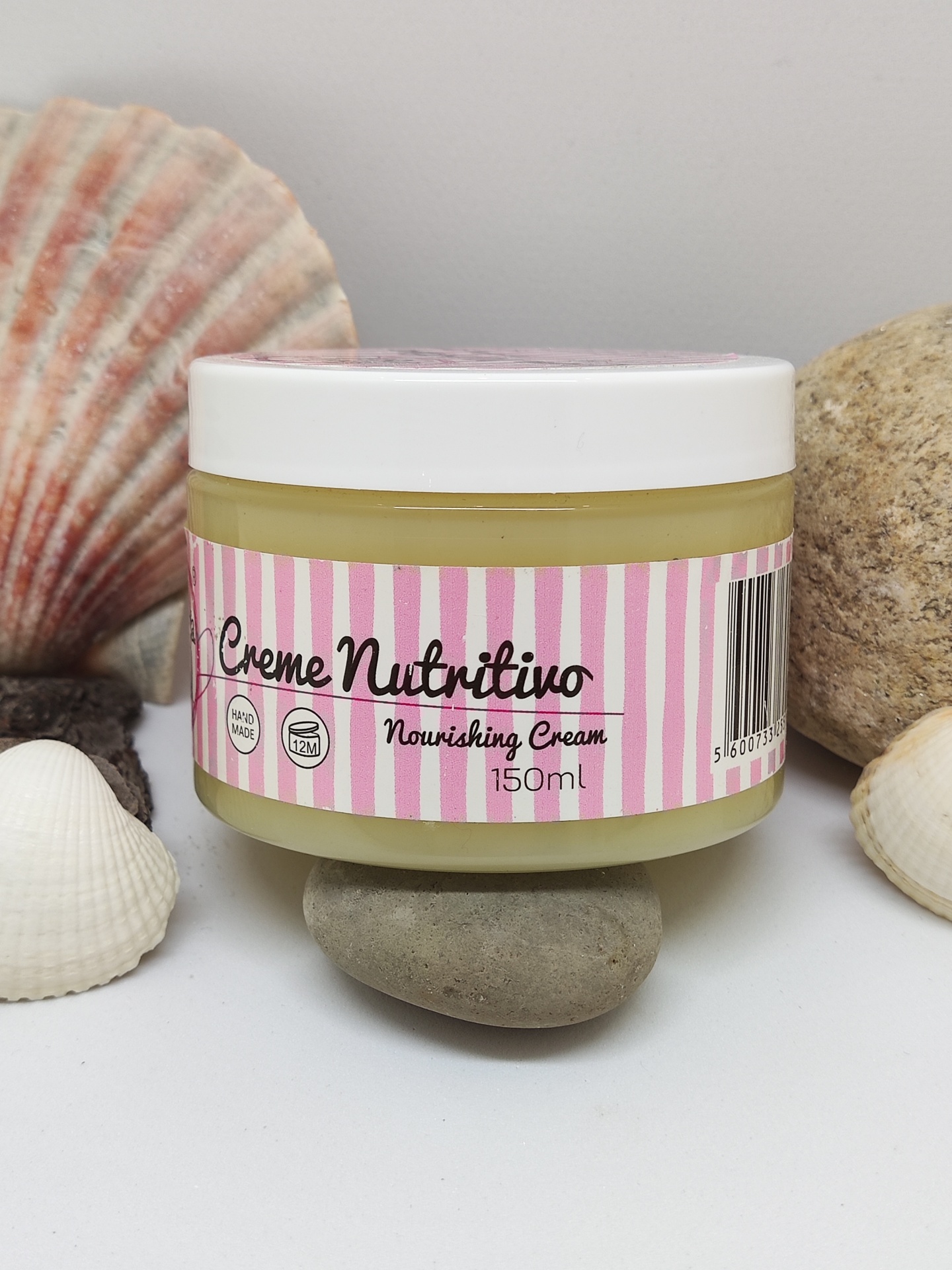 Frasco de creme nutritivo com tampa branca e etiqueta rosa às riscas com conchas e pedras