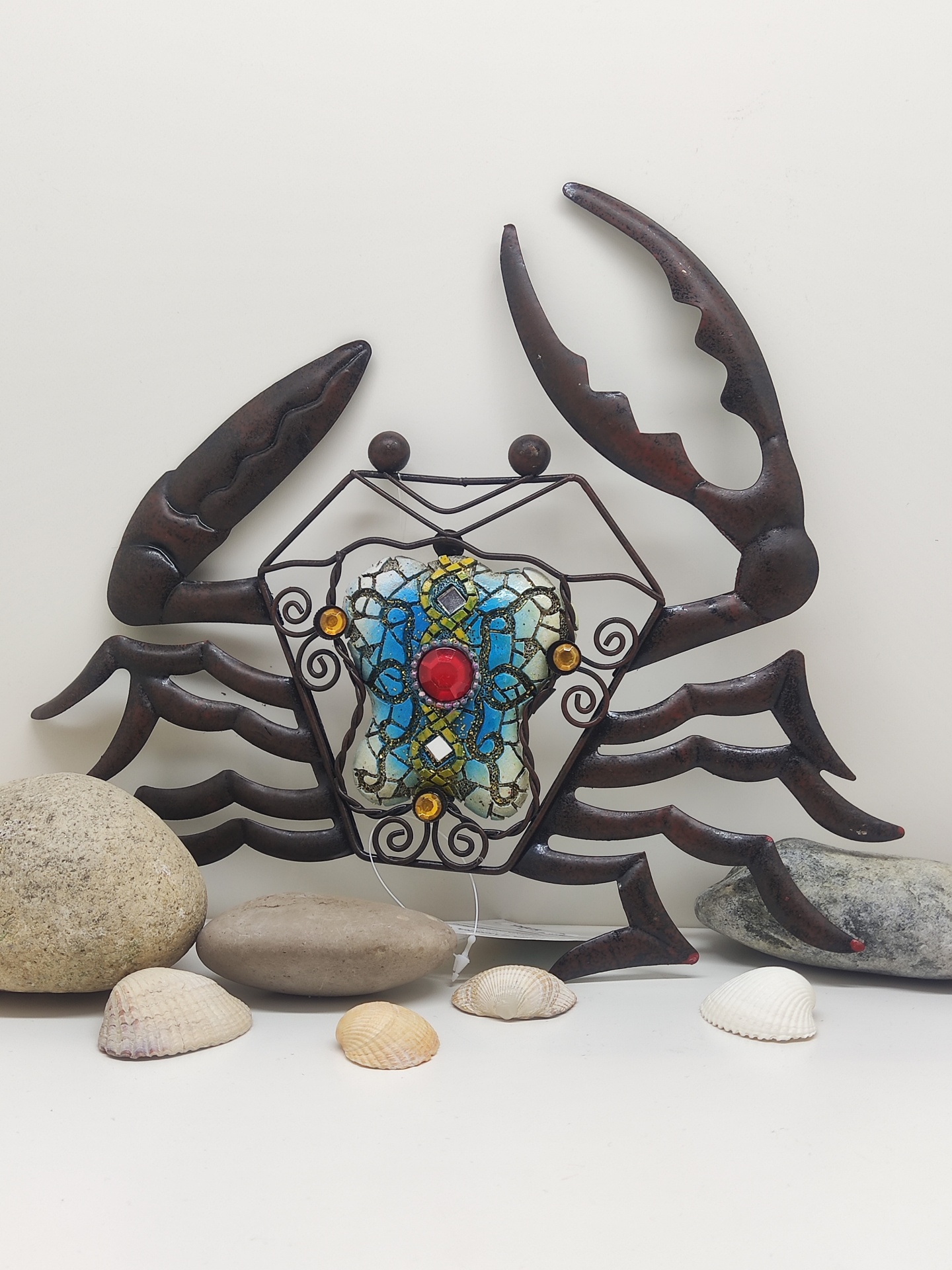 Escultura decorativa de caranguejo de metal com vidro colorido e pedras à frente