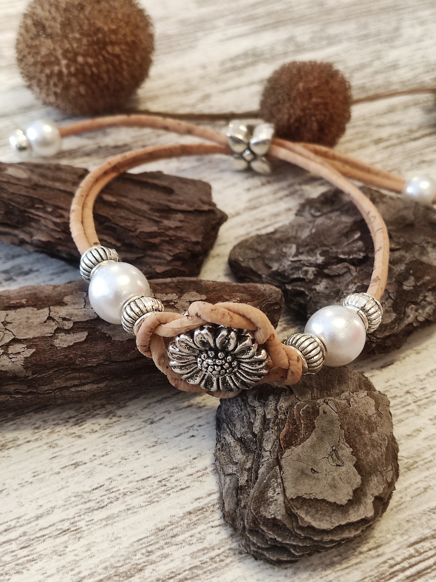 Pulseira ajustável de couro bege com pérolas e contas metálicas prateadas sobre madeira