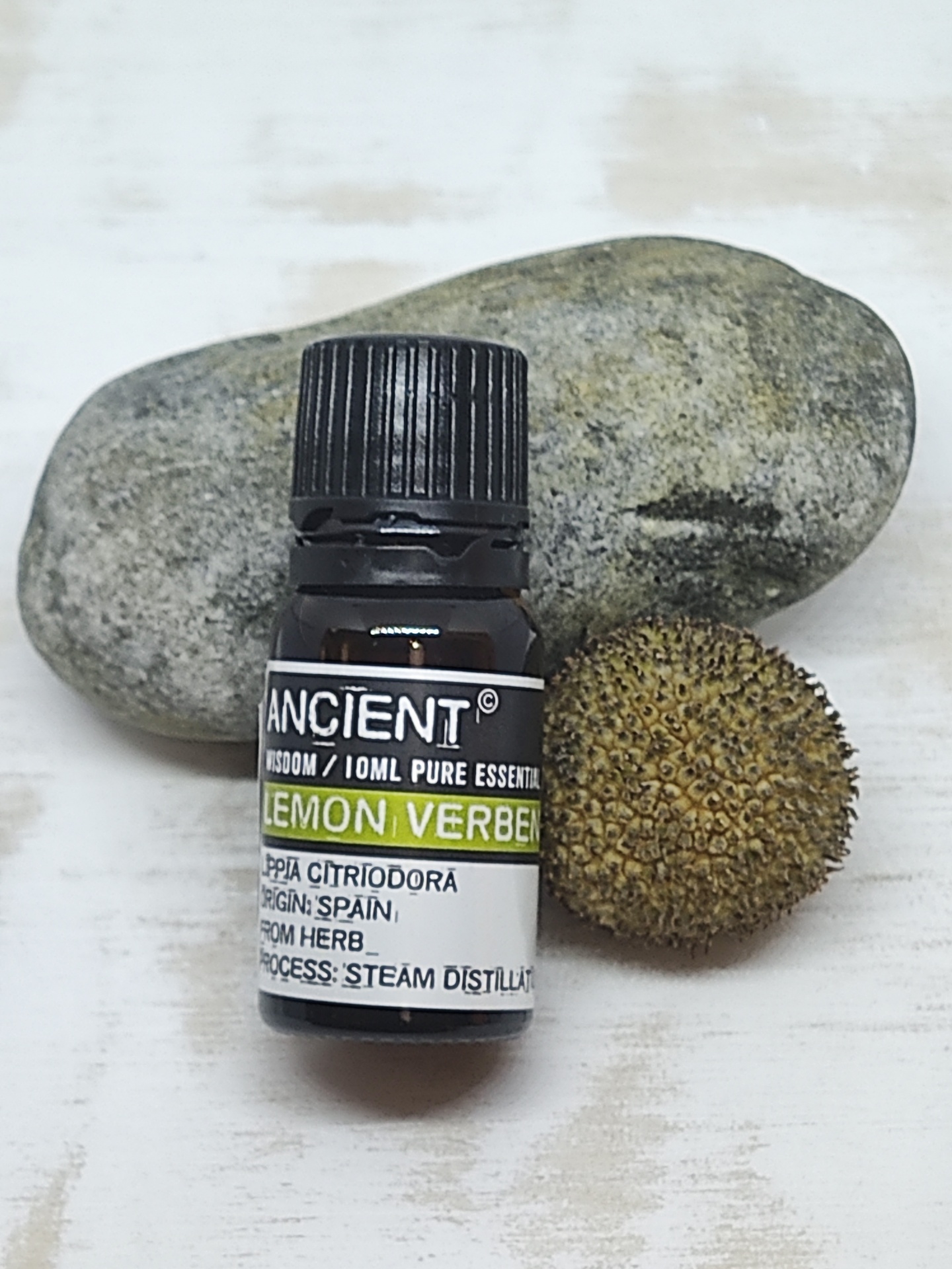 Frasco de óleo essencial Lemon Verbena com pedra e semente ao fundo