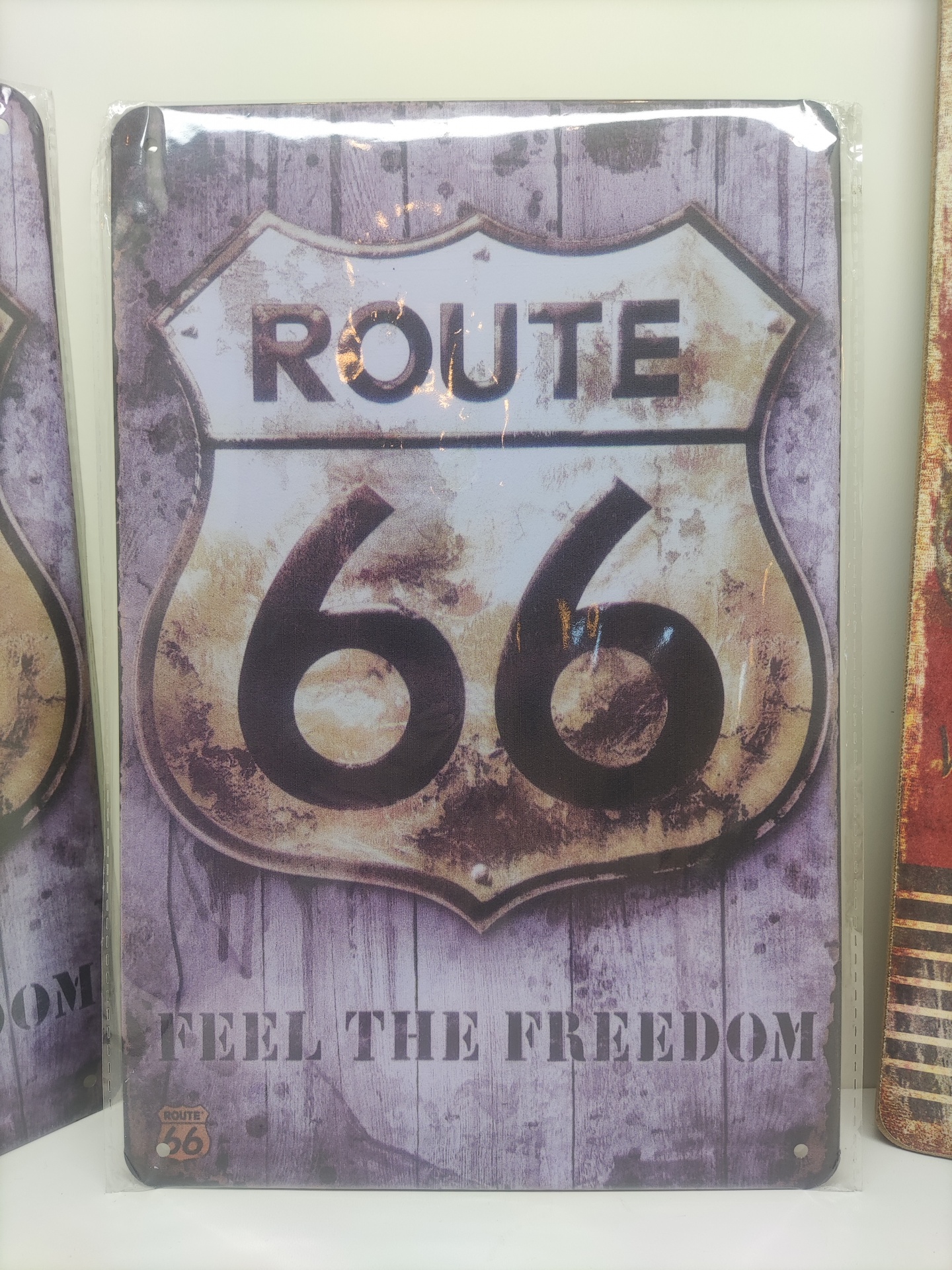 Placa metálica decorativa Route 66 com fundo roxo e texto FEEL THE FREEDOM