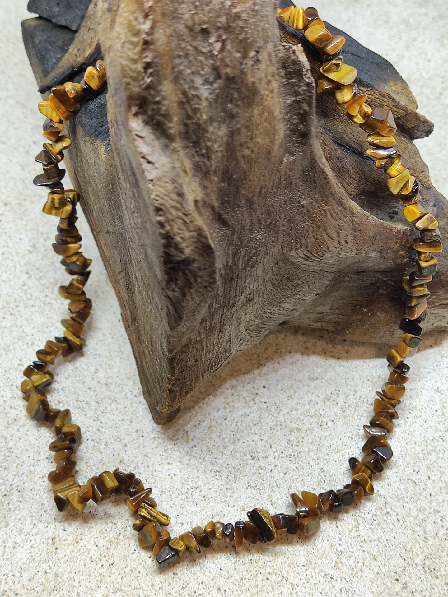 Colar de pedras naturais castanhas e amarelas sobre madeira