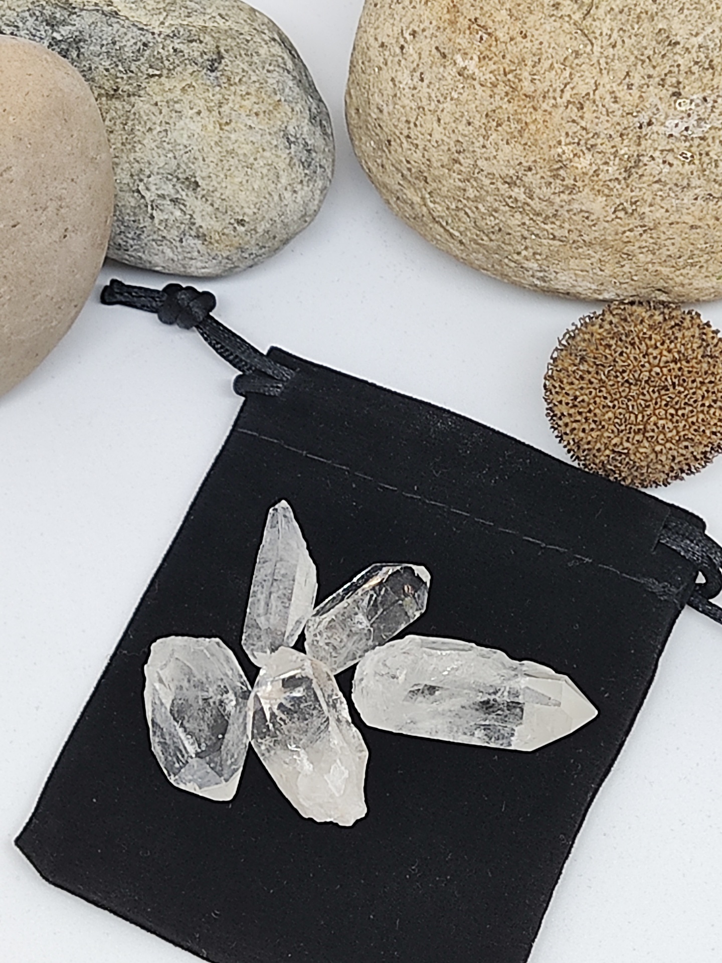 Cristais transparentes sobre bolsa de tecido preto com pedras ao redor