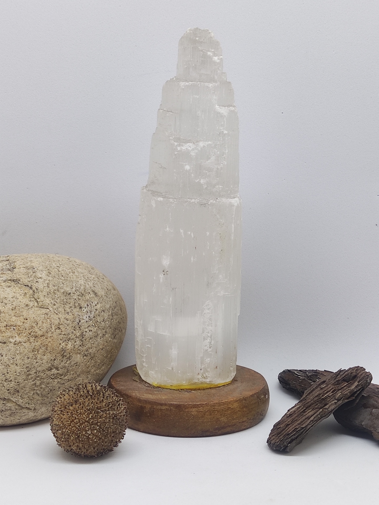 Cristal translúcido branco em base de madeira com pedras e madeira ao lado