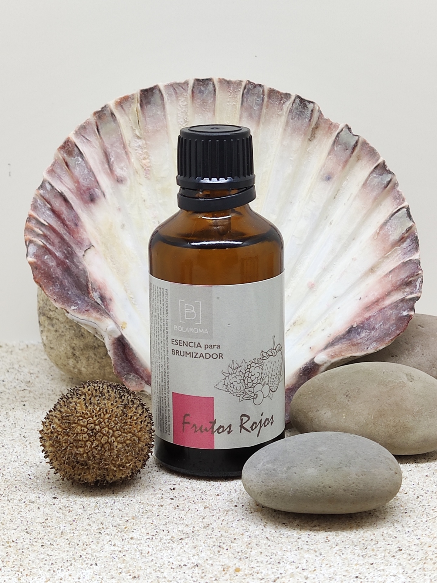 Frasco de essência para brumizador em frasco âmbar com pedras e concha ao fundo