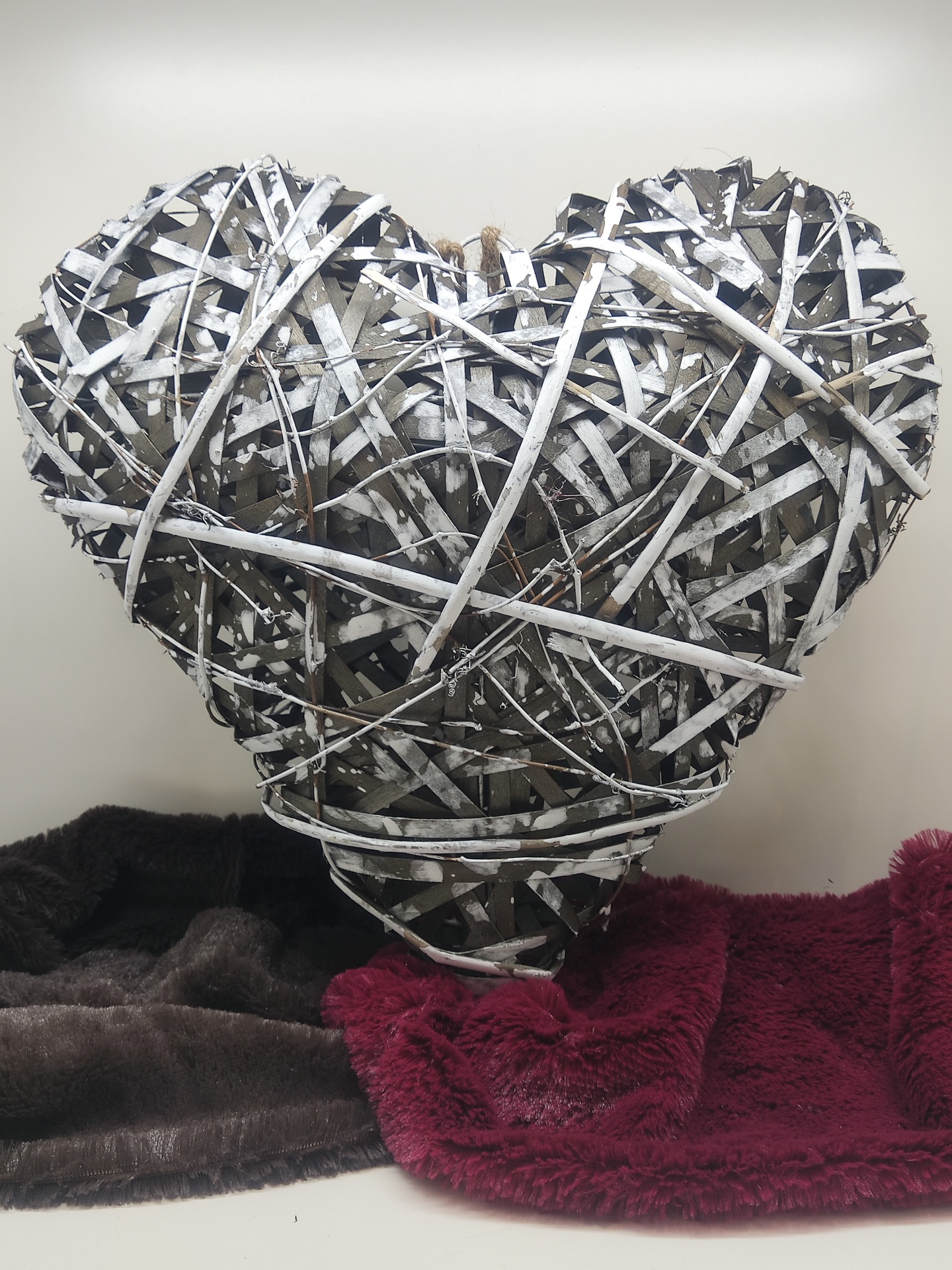 Coração decorativo feito de ramos entrelaçados sobre tecidos macios