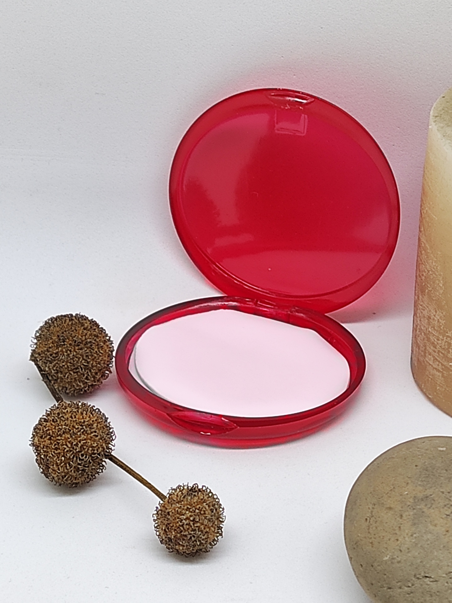 Espelho compacto redondo vermelho com frutos secos, vela e pedra