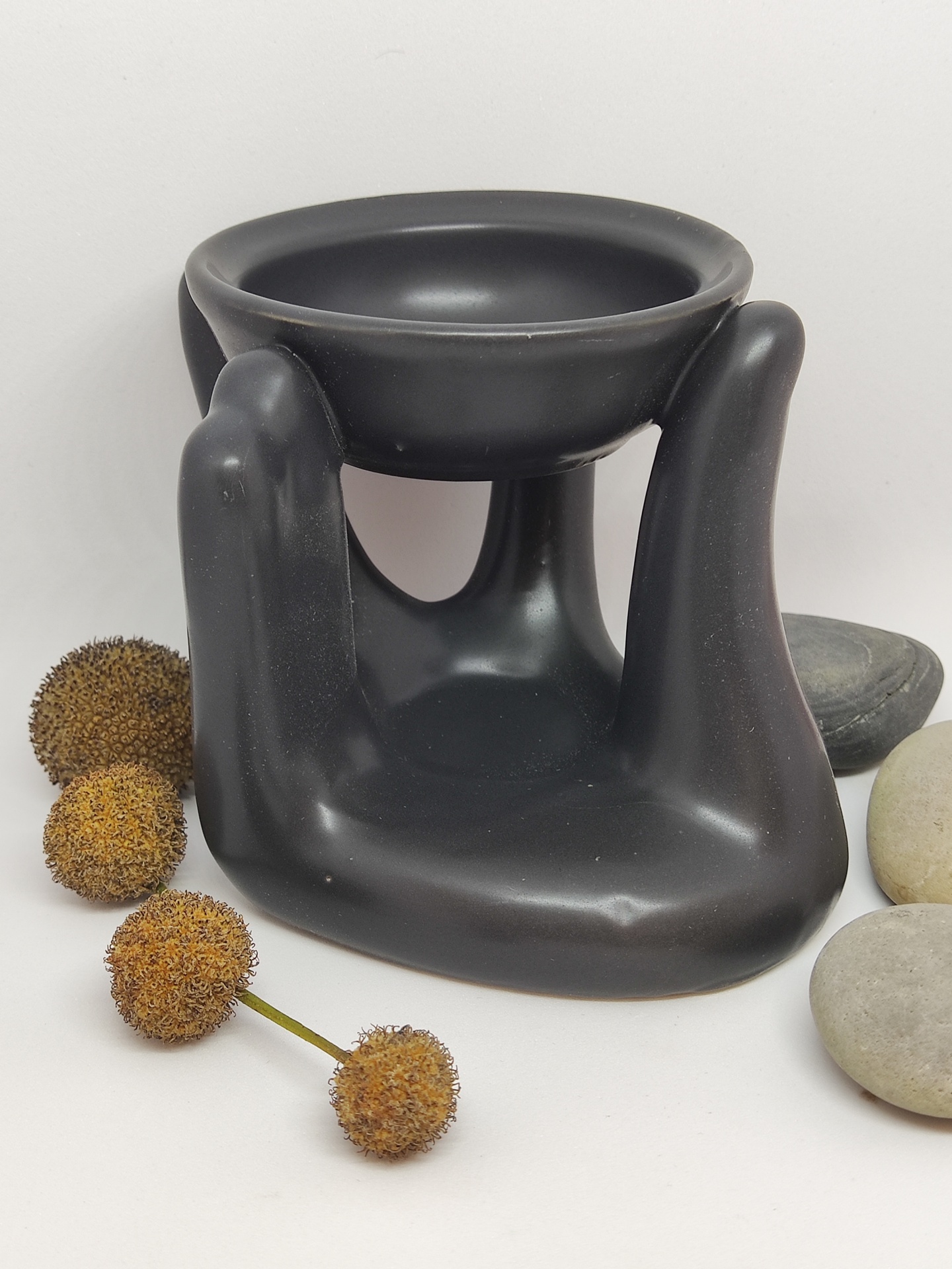 Aromatizador em forma de mão com pedras e flores secas ao lado