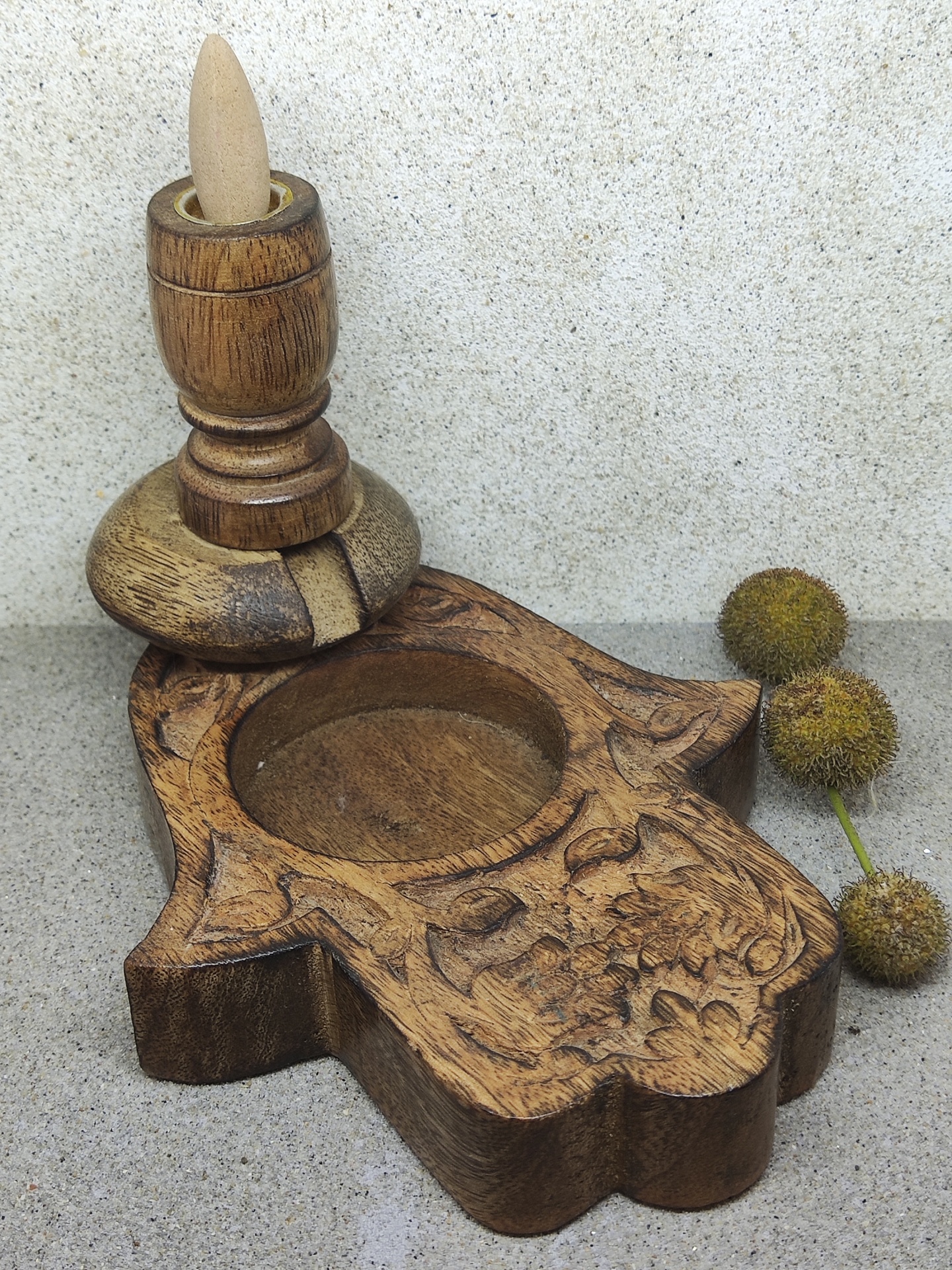 Suporte de madeira para incenso com cone e flores secas ao lado