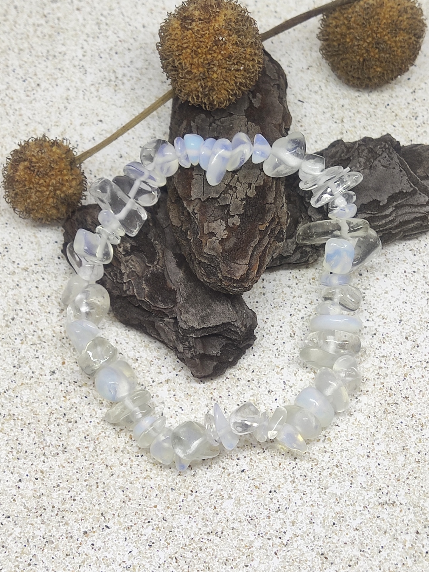 Pulseira de pedras iridescentes brancas e translúcidas sobre casca e fundo claro