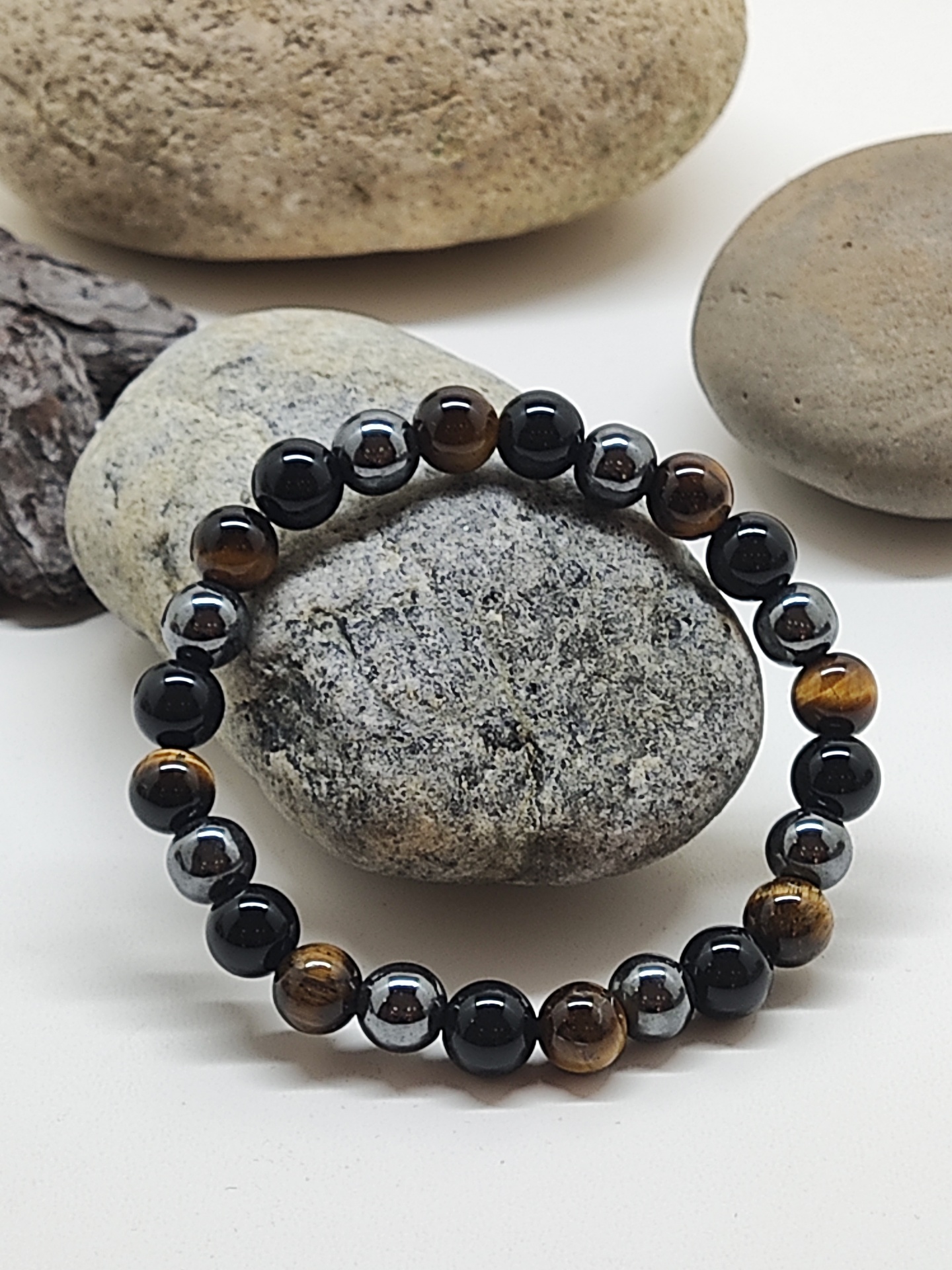 Pulseira de contas cinza metálico, castanho e preto sobre pedras naturais