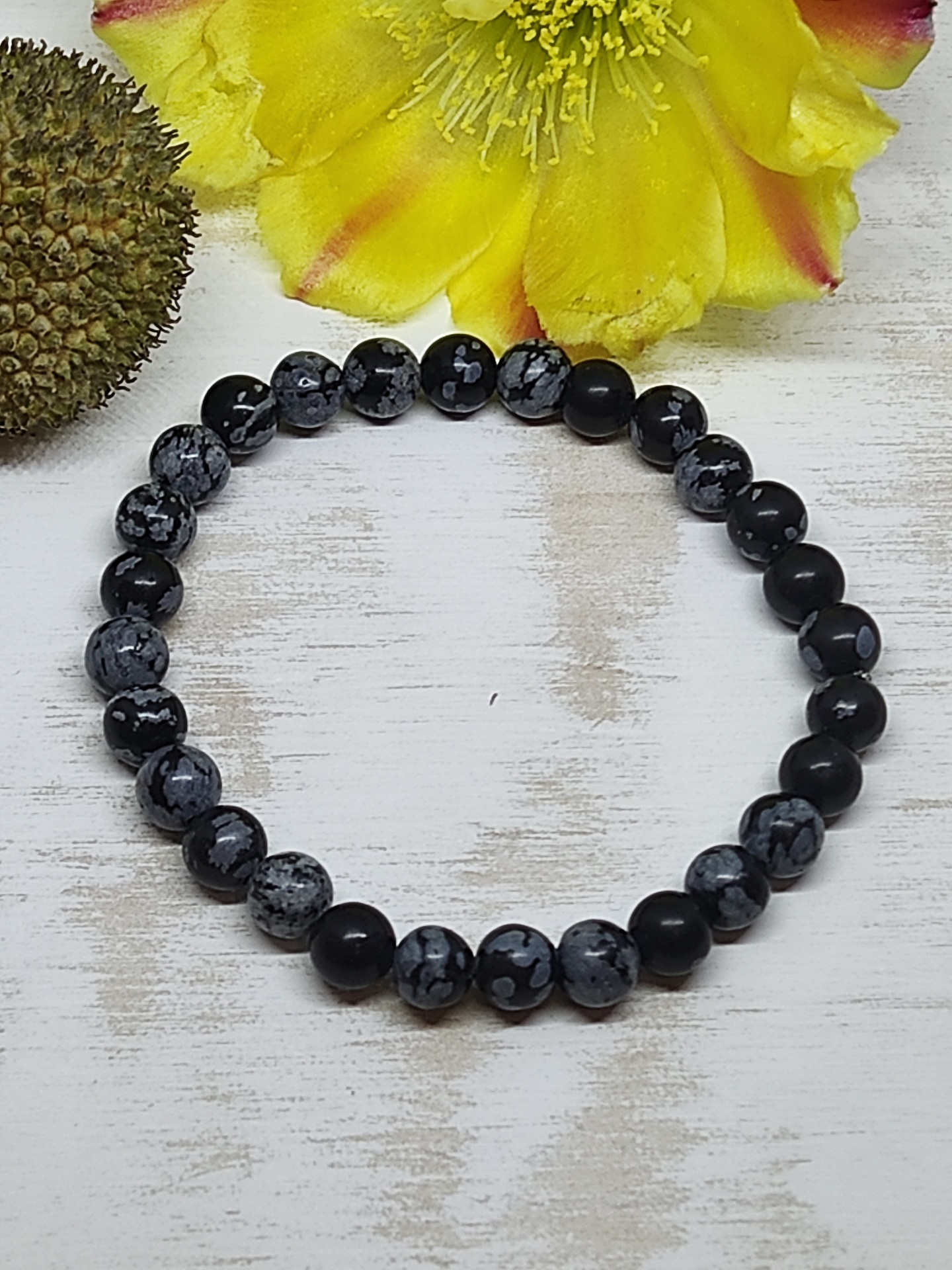 Pulseira de contas pretas e cinza com padrão de manchas brancas