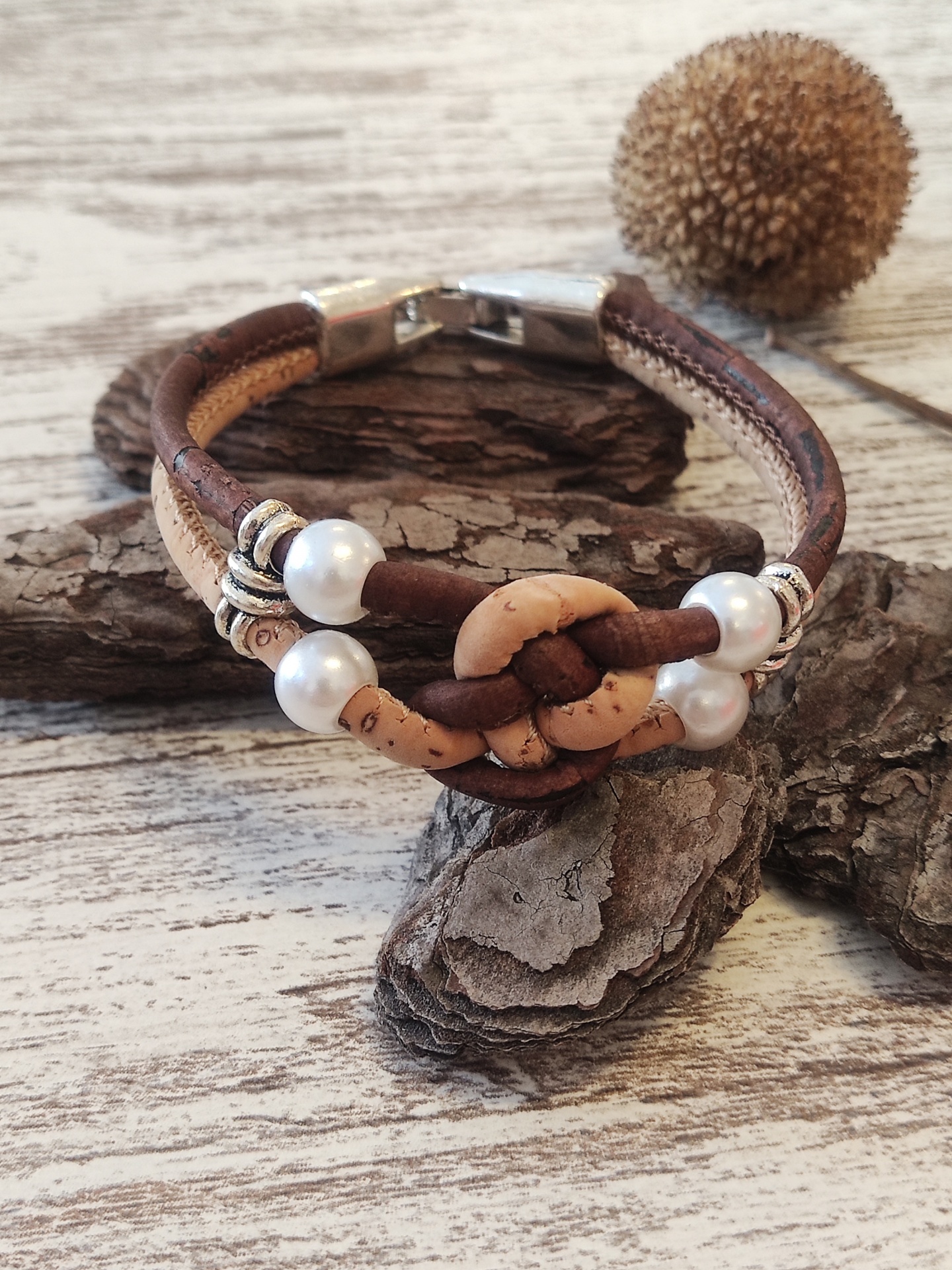Pulseira de couro castanho e pérolas brancas sobre madeira rústica