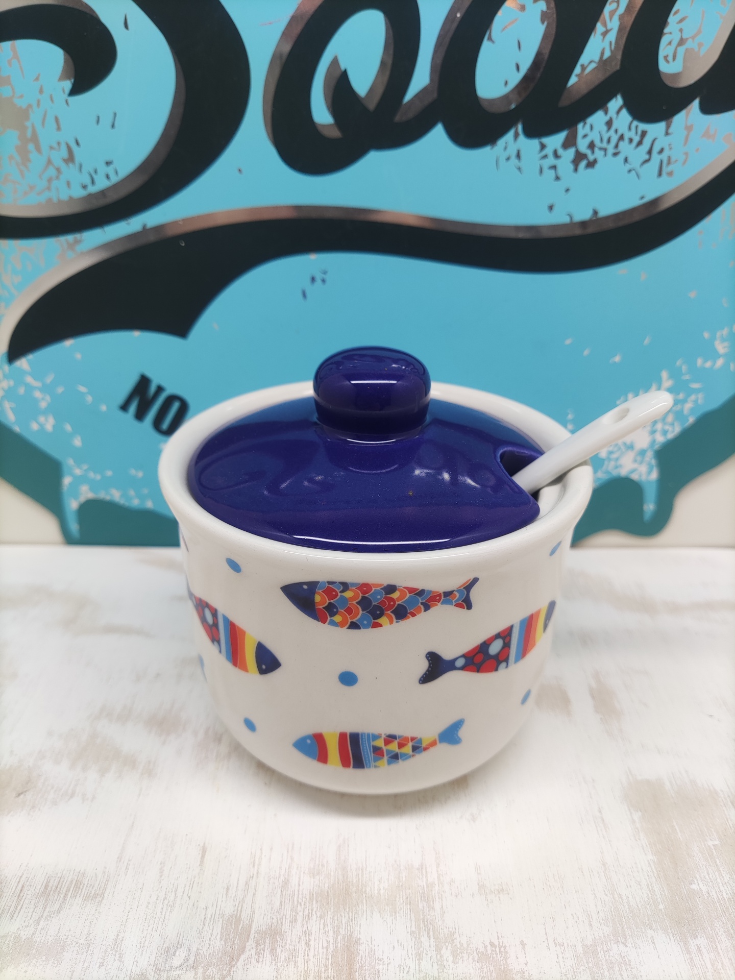Pote cerâmico com tampa azul e decoração de peixes coloridos.