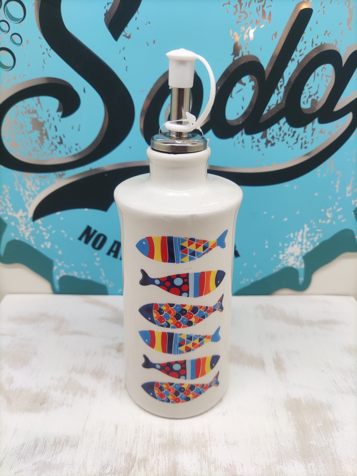 Garrafa doseadora branca com peixes coloridos e tampa metálica